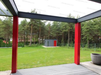Záhradný domček v tmavo-sivej omietke s červenými dverami na záhrade