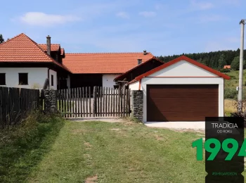 Garáž pro dvě auta se špičatou střechou u domu se sedlovou střechou