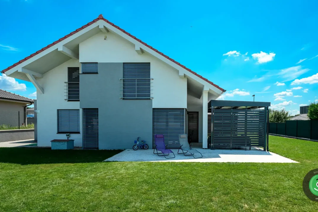 Bílo-šedý rodinný dům s montovanou černou pergolou