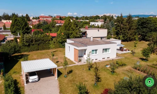 Přístřešek pro dvě auta s bílou střechou vedle bílého domu.