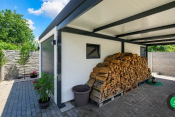 Úložný prostor pro dřevo pod přístřeškem vedle garáže