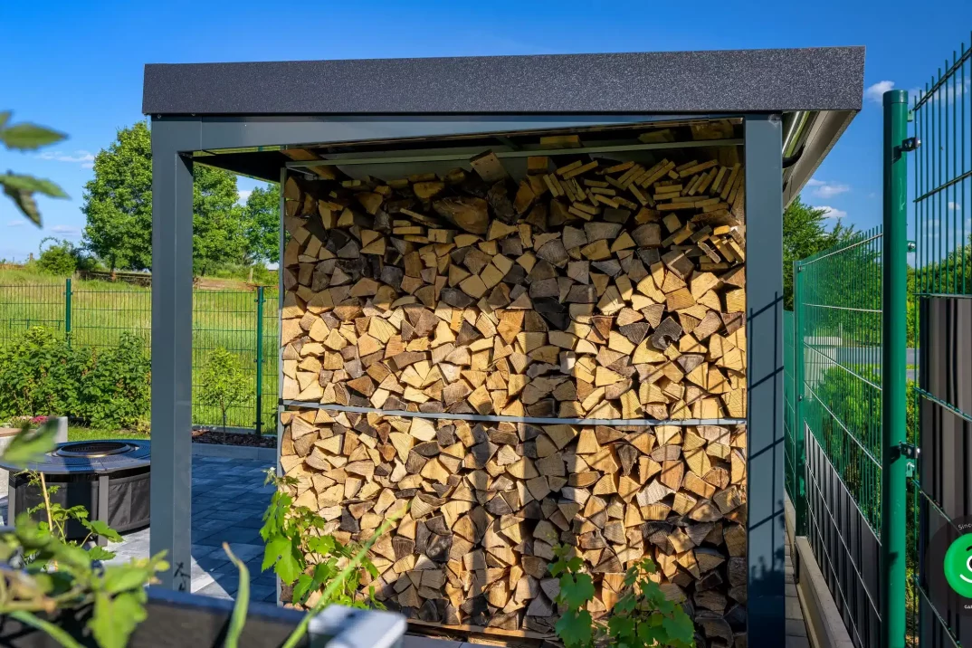 Dřevo uložené pod přístřeškem vedle zahradního domku