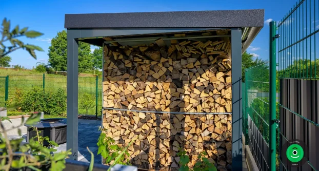 Dřevo uložené pod přístřeškem vedle zahradního domku