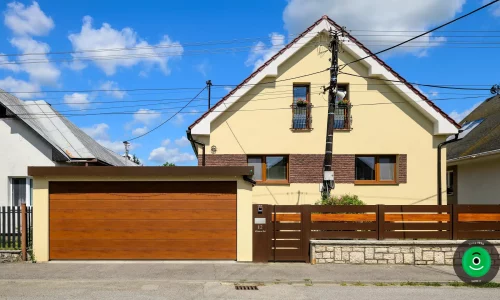 Montovaný přístřešek se žlutou omítkou a širokými hnědými garážovými vraty