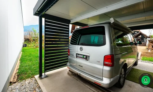 auto pod přístřeškem s černou kovovou výplní