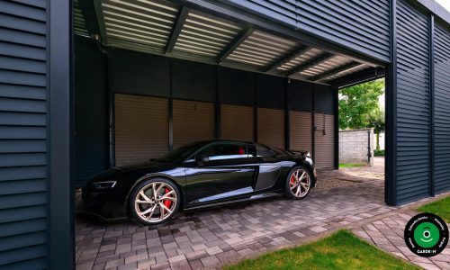 Luxusní černý sporťák zaparkovaný pod kovovým přístřeškem.