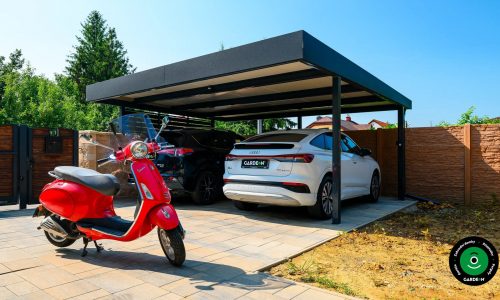 Černý přístřešek pro dvě auta s kontrastní cihlovou stěnou a oplocením.