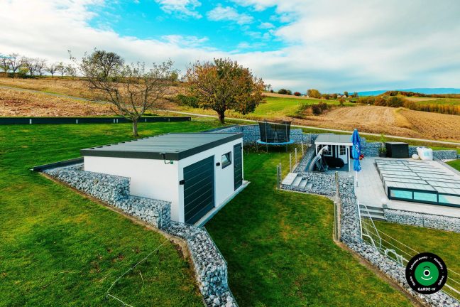 Garáž na svahu obklopená gabiony a udržovaným zeleným trávníkem