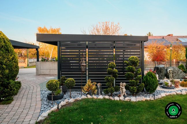 Boční stěna přístřešku u okrasných dřevin a kamínků