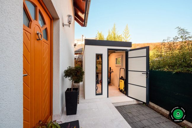 Zahradní domek u domu s otevřenými dveřmi a vybavením