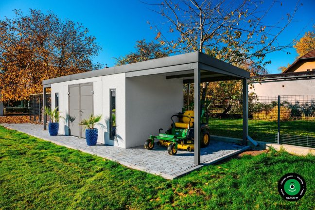 Praktický montovaný domek s betonovým chodníkem a zeleným pozadím