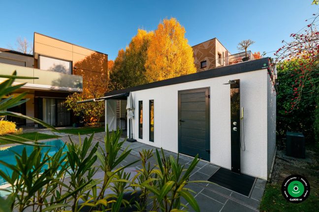 Zahradní domek u bazénu obklopený podzimními stromy