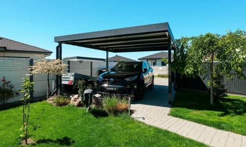 Prostorný přístřešek pro auto umístěný u upravené moderní zahrady