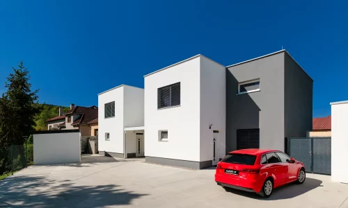 Moderní zahradní domek s přístřeškem u minimalistického rodinného domu