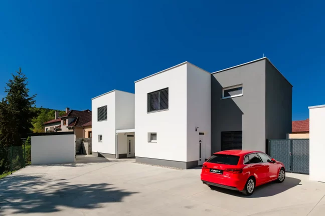 Moderní zahradní domek s přístřeškem u minimalistického rodinného domu