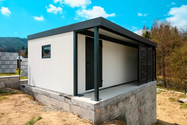 Stylový zahradní domek s antracitovou konstrukcí a moderním krytým přístřeškem
