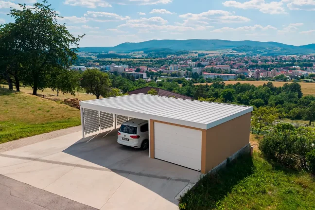 Kombinovaná stavba garáže a přístřešku s cihlovou omítkou a bílou střechou.