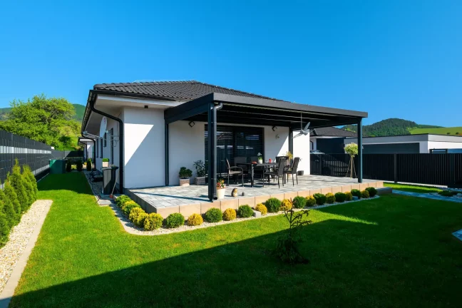 Pergola s antracitovou konstrukcí u bílého domu, zelený trávník