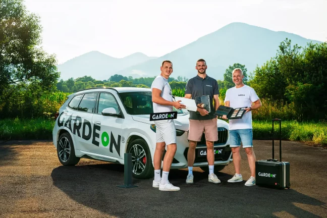 Trio agentů GARDEON s materiály a kufříkem u firemního BMW.
