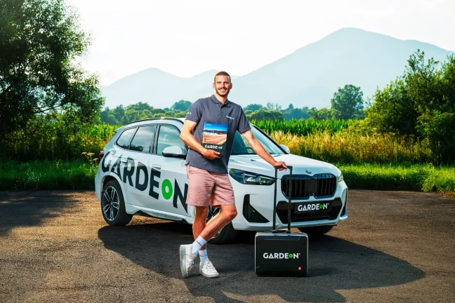 Zaměstnanec GARDEON se vzorníkem a kufříkem před firemním BMW v přírodě.
