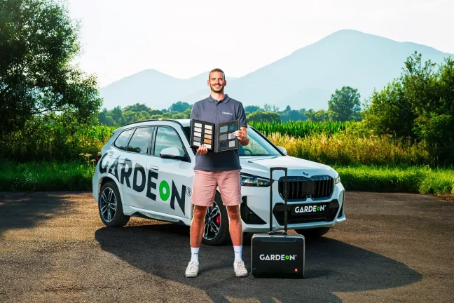 Obchodní agent GARDEON drží vzorník barev před firemním BMW.