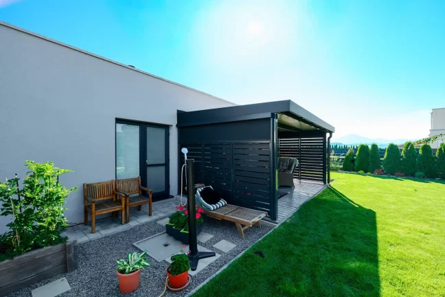 Antracitová pergola s kovovou výplní v zahradě rodinného domu.
