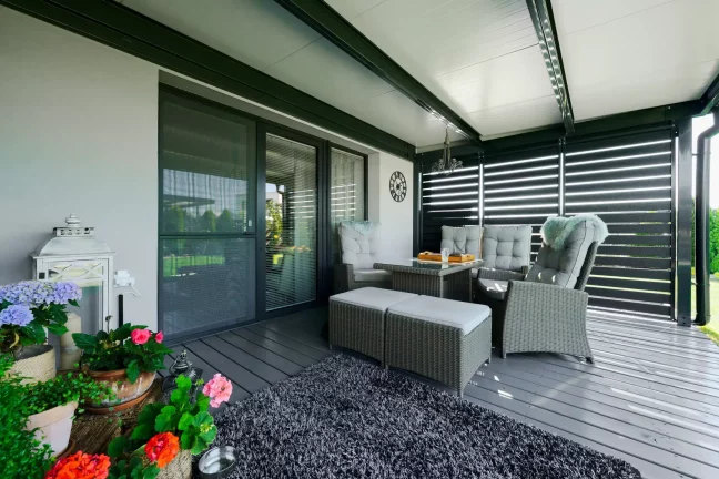 Antracitová pergola s kovovými lamelami a ratanovým sezením na terase.