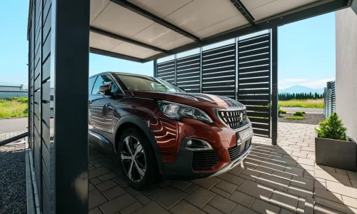 Přístřešek s antracitovou kovovou výplní s parkujícím SUV.