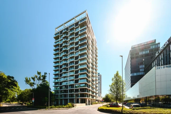 Moderní výšková budova s prosklenými balkony a bílou konstrukcí fasády