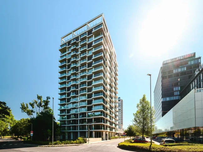 Moderní výšková budova s prosklenými balkony a bílou konstrukcí fasády