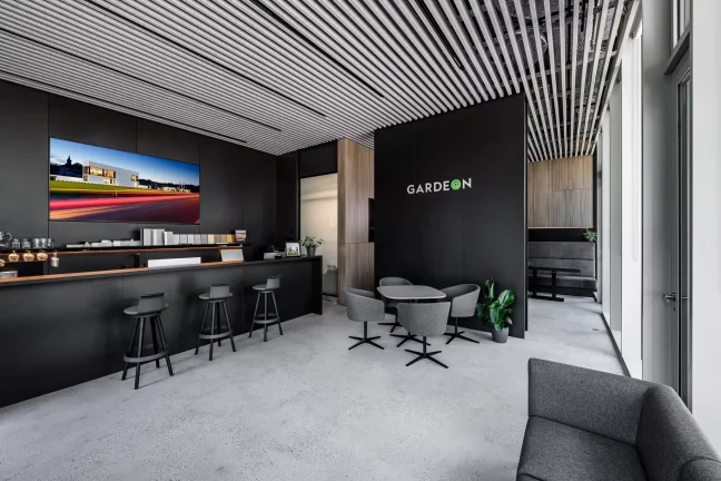 Moderní showroom GARDEON s černou stěnou, barovým pultem a lamelovým stropem