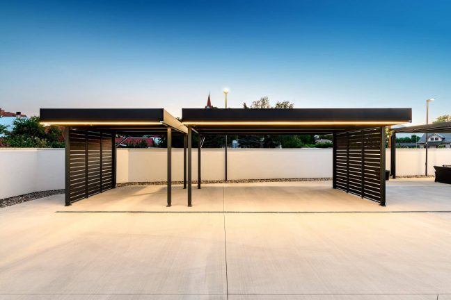 Dvojitý carport s tmavou kovovou výplní a LED podsvícením atiky.