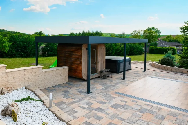 Antracitová pergola u bazénu s průhledným zastřešením, bílý štěrk a dlážděná plocha kolem