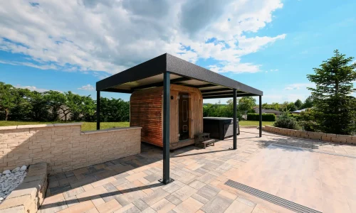 Volně stojící antracitová pergola s plochou střechou na dlážděné terase, zelená zahrada v pozadí