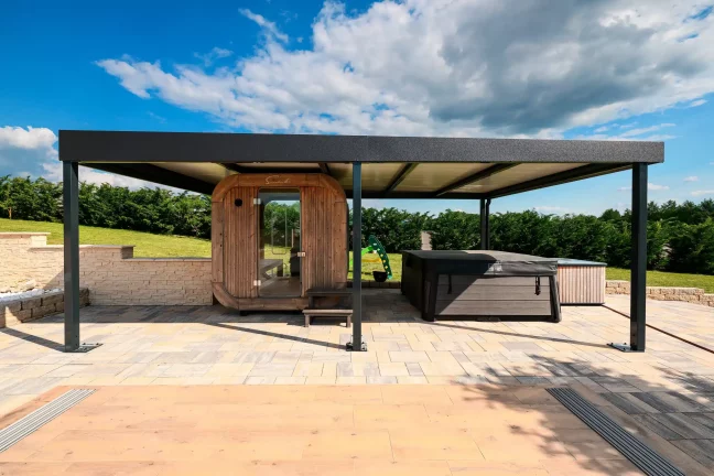 Antracitová pergola s plochou střechou u sudové sauny na dlážděné terase