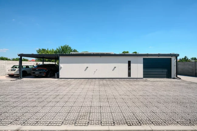 Přední pohled na dům se zeleným autem Gardeon a solární stěnou