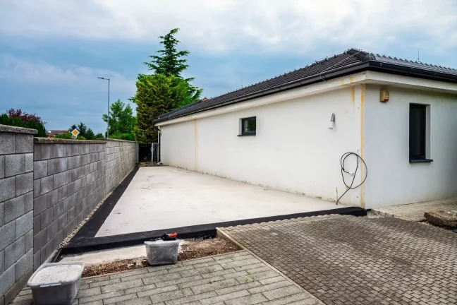 Připravená betonová plocha u domu před montáží garáže