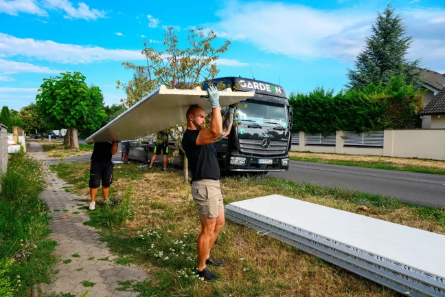 Pracovník vykládá zabalený stěnový panel z nákladního auta Gardeon