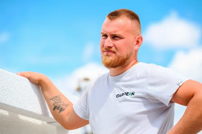 Portrét montážníka Gardeon opřeného o bílou stěnu garáže