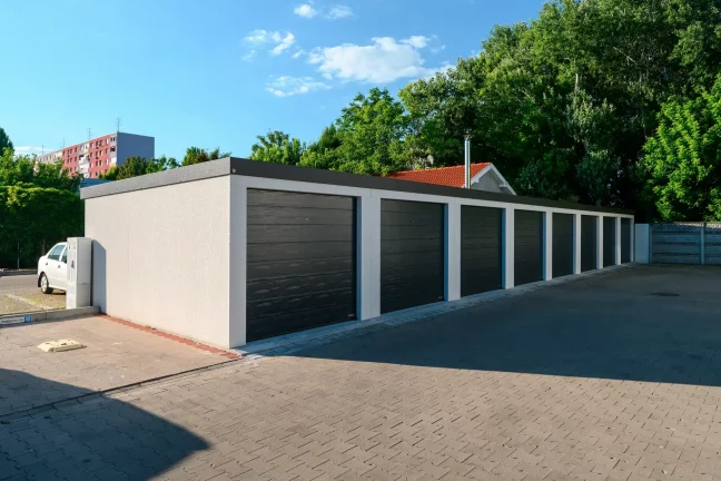 Řada tmavých garáží v ranním světle s bílým autem