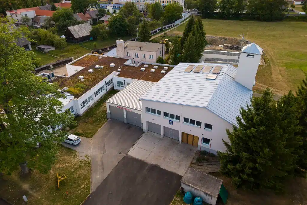 Letecký pohled na hasičskou zbrojnici s garážemi v obci obklopené zelení