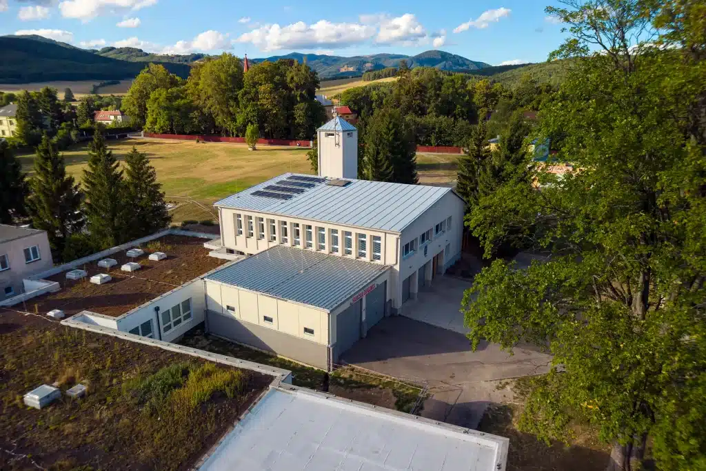 Pohled z dronu na hasičskou zbrojnici s novou garáží a věží na pozadí hor