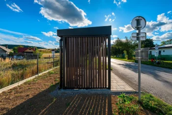 Přístřešek zastávky z boku s dopravní značkou u silnice