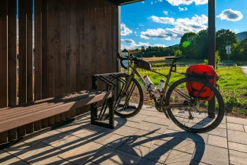 Kolo ve stojanu u lavičky pod přístřeškem zastávky
