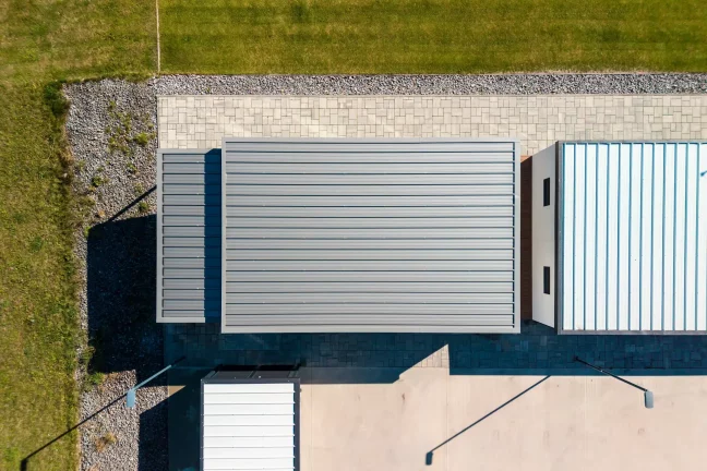 Pohled z dronu na plochou střechu tiny housu a sousedních staveb v showroomu