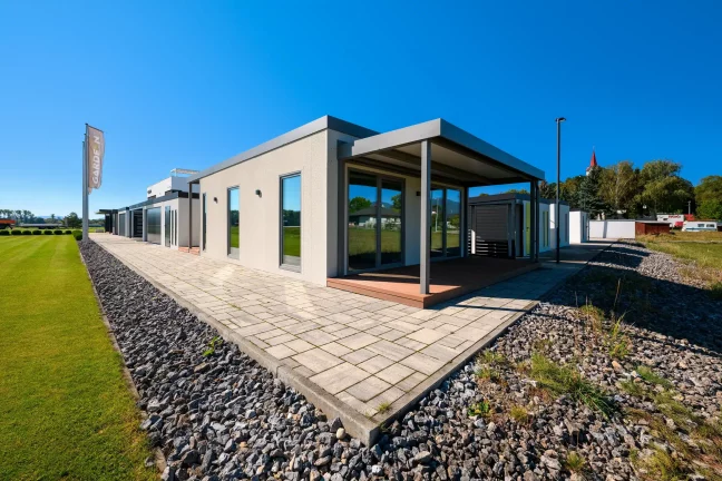 Tiny house s krytou terasou a dlážděným chodníkem podél trávníku
