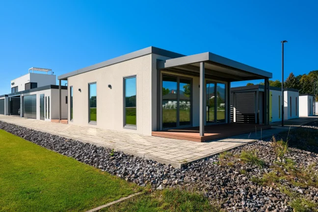 Přední roh tiny housu s krytou terasou a velkými prosklenými dveřmi