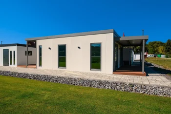 Boční pohled na tiny house s krytou terasou a štěrkovým lemem