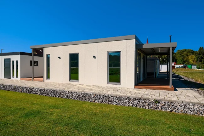 Boční pohled na tiny house s krytou terasou a štěrkovým lemem