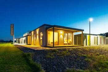 Přední roh osvětleného tiny housu s krytou terasou za soumraku
